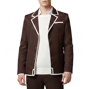 May include: A brown blazer with white trim and a white sweater underneath. The blazer has a pocket on the chest and is paired with matching brown pants. The outfit is set against a white background.