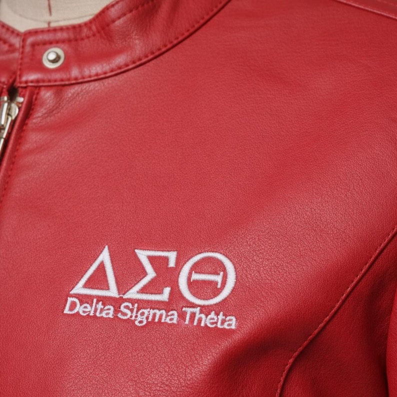May include: A close-up of a red leather jacket with a silver zip and a snap closure at the collar. The jacket features the embroidered Greek letters Delta Sigma Theta in white.