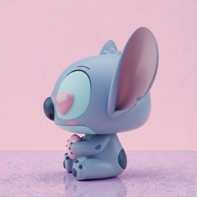 May include: A blue and gray figurine of a cartoon character with large ears, holding a pink heart-shaped object. The figurine has a heart-shaped nose and a single large eye. The background is a gradient of pink and purple.