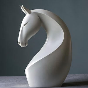 May include: A white horse head sculpture with a modern design. The sculpture has a curved neck and detailed head, with closed eyes and pointed ears. The artwork is a decorative piece.