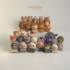 May include: A collection of small, sculpted animal figurines designed as mechanical keyboard keycaps. The set features various creatures including a panda, raccoon, penguin, pig, frog, shark, whale, and lion, each mounted on a square base.