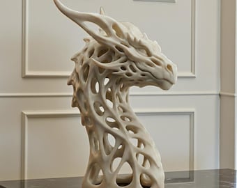 May include: A cream-colored dragon head sculpture with an open, lattice-like design. The sculpture features a detailed face, horns, and a long neck. The artwork is displayed on a black marble surface.