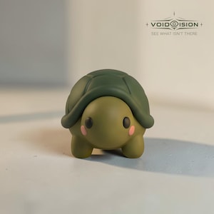 May include: A small turtle figurine with a dark green shell and a light olive green body. The turtle has two black eyes and small pink circular markings on its cheeks. The text VOID VISION SEE WHAT ISN'T THERE is visible in the upper right corner.