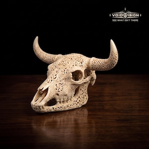 May include: An off-white bull skull sculpture featuring intricate, carved Celtic knotwork and a triskelion symbol on the forehead. The surface is covered in detailed, swirling patterns and geometric designs. The logo VOIDISION SEE WHAT ISN'T THERE is visible.