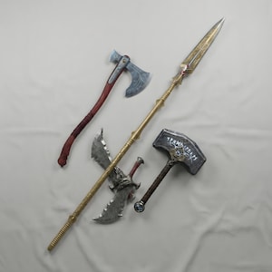 May include: Four fantasy weapons are displayed against a white background. The weapons include a silver axe with a brown handle, a gold spear, a silver double-bladed axe, and a hammer with a dark handle and engraved details.