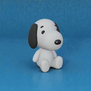 Może przedstawiać: Biała figurka Snoopy'ego z czarnymi uszami i nosem siedzi na niebieskiej powierzchni. Figurka ma teksturowaną powierzchnię i jest w pozycji siedzącej. Postać z kreskówki jest popularnym przedmiotem kolekcjonerskim.