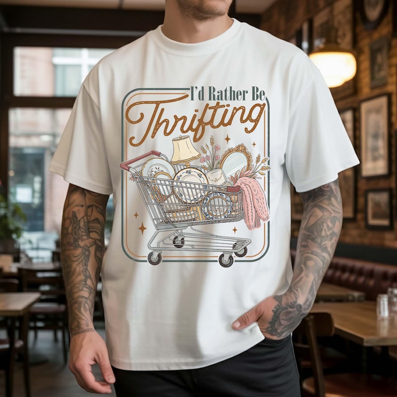 PNG digital design featuring a vintage-style illustration of a shopping cart filled with thrifted items and the phrase “I’d Rather Be Thrifting” in retro typography, isolated on transparent background.