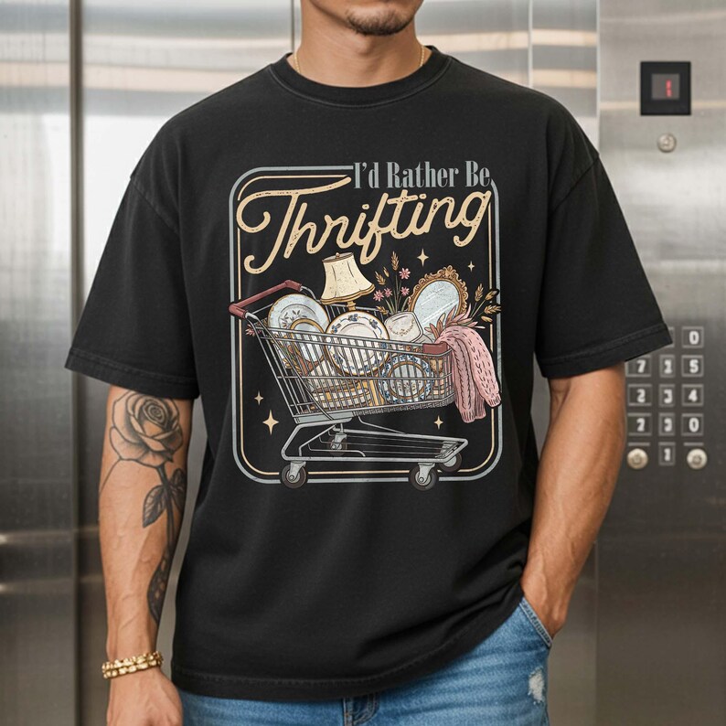 PNG digital design featuring a vintage-style illustration of a shopping cart filled with thrifted home decor items and the phrase “I’d Rather Be Thrifting,” displayed on a black t-shirt mockup.