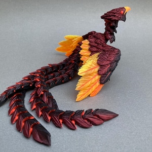 May include: A detailed figurine of a phoenix bird, featuring a vibrant color palette. The sculpture showcases a combination of red, black, yellow, and orange hues. The bird's feathers are meticulously crafted, and the figure is posed on a gray surface.
