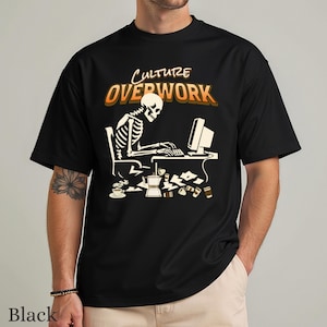 May include: A black short-sleeve t-shirt featuring a graphic of a skeleton sitting at a desk using a computer. The text "CULTURE OVERWORK" is printed above the skeleton. Scattered on the desk and floor are several coffee cups and a coffee pot.