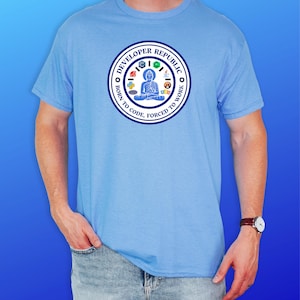 May include: Light blue t-shirt with a circular graphic. The graphic features a seated figure and the text "DEVELOPER REPUBLIC" around the edge, with the phrases "BORN TO CODE" and "FORCED TO WORK".