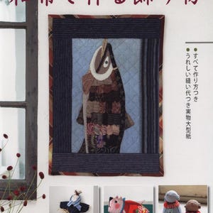 May include: A book cover with a quilted fish design in a framed presentation. The fish is made of various fabric scraps in brown, beige, and blue hues. The title in Japanese reads "Decorations Made with Japanese Fabric."