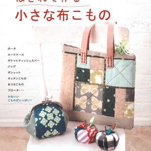 May include: A book cover with Japanese text, a tote bag, a coin purse, and fabric apples. The tote bag features a patchwork design with butterfly and geometric patterns. The coin purse is blue with a floral pattern. The apples are made of fabric.