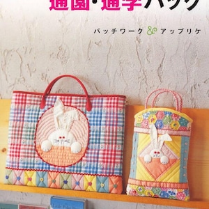 Puede incluir: Dos bolsos tote acolchados con apliques de conejos. El bolso más grande tiene asas rojas y un estampado de cuadros rojos, blancos y azules. El bolso más pequeño tiene un fondo amarillo con detalles florales y de conejos. Texto japonés visible.