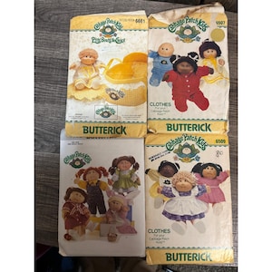 May include: Four vintage Butterick sewing patterns for Cabbage Patch Kids dolls. The patterns feature illustrations of the dolls in various outfits. The patterns are labeled with the Cabbage Patch Kids logo and the Butterick brand.
