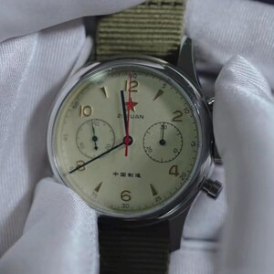 May include: A vintage-style wristwatch with a cream-colored face, black numerals, and a red star at the 12 o'clock position. The watch has two sub-dials and a green canvas strap. The text "Zuan" and Chinese characters are visible on the watch face.