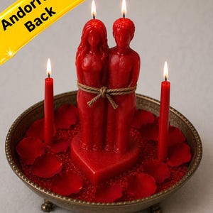 May include: A red candle set featuring a couple figurine tied together, set on a heart-shaped base. The candles are in a decorative metal dish with red rose petals and small red beads. The text "Andorra is Back" is in the image.