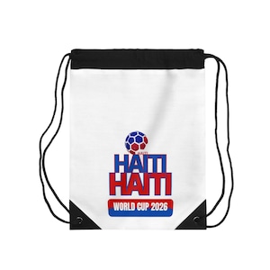 Puede incluir: Bolsa con cordón blanca con la parte superior negra y cordones negros. La bolsa presenta el texto "HAITI" en rojo y azul, con un gráfico de balón de fútbol y las palabras "WORLD CUP 2026".