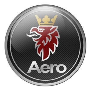 Könnte beinhalten: Rundes Emblem mit silbernem Rand und Karbonfaser-Hintergrund. Das Emblem zeigt einen roten Greif mit goldener Krone und das Wort "Aero" in Silber.