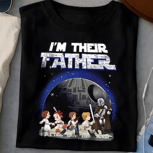以下が含まれることがあります： 「I'M THEIR FATHER」の文字とデス・スター、スター・ウォーズのキャラクターが描かれた黒いTシャツ。キャラクターの下には、Sophia、Emily、James、Ethan、Michaelの名前が書かれています。