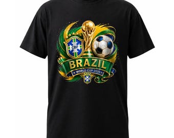 May include: A black short-sleeve t-shirt featuring a graphic print of the gold World Cup trophy, a soccer ball, and the CBF crest. A green ribbon banner displays the text BRAZIL and WORLD CUP 2026, surrounded by swirling green and yellow accents.
