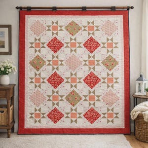May include: A rectangular quilt featuring a repeating pattern of star blocks and diamond-shaped fabric patches in shades of red, pink, beige, and green. The quilt is framed by a wide red border and is suspended from a dark wooden rod.