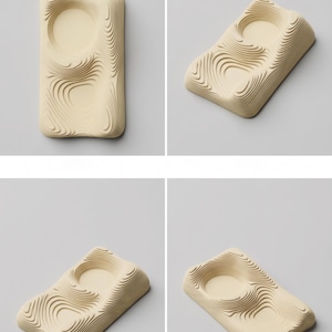 May include: A set of four beige, rectangular trays with a unique, layered design. Each tray features a circular indentation and a series of curved, wave-like patterns. The trays are displayed against a neutral gray background, showcasing their minimalist aesthetic.
