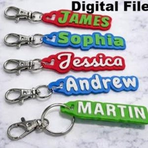 Peut inclure: Cinq porte-clés personnalisés avec des noms et des fermoirs argentés. Les noms sont "JAMES", "Sophia", "Jessica", "Andrew" et "MARTIN". Chaque porte-clés a une combinaison de couleurs différente : rouge et vert, bleu et vert, rouge et blanc, bleu et blanc, et vert et blanc. Les mots "Digital Files" sont en haut.