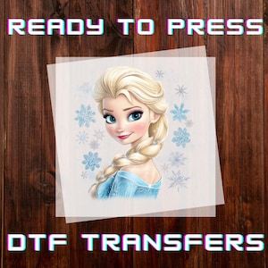 May include: A DTF transfer featuring a cartoon illustration of a blonde woman with blue eyes and a blue dress, surrounded by snowflakes. The text "READY TO PRESS" and "DTF TRANSFERS" are displayed in a colorful font.