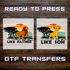 May include: Two square DTF transfer designs featuring lion illustrations. One design shows a lion with the text "LIKE FATHER", and the other shows a lion cub with the text "LIKE SON". The background includes a sunset and trees.