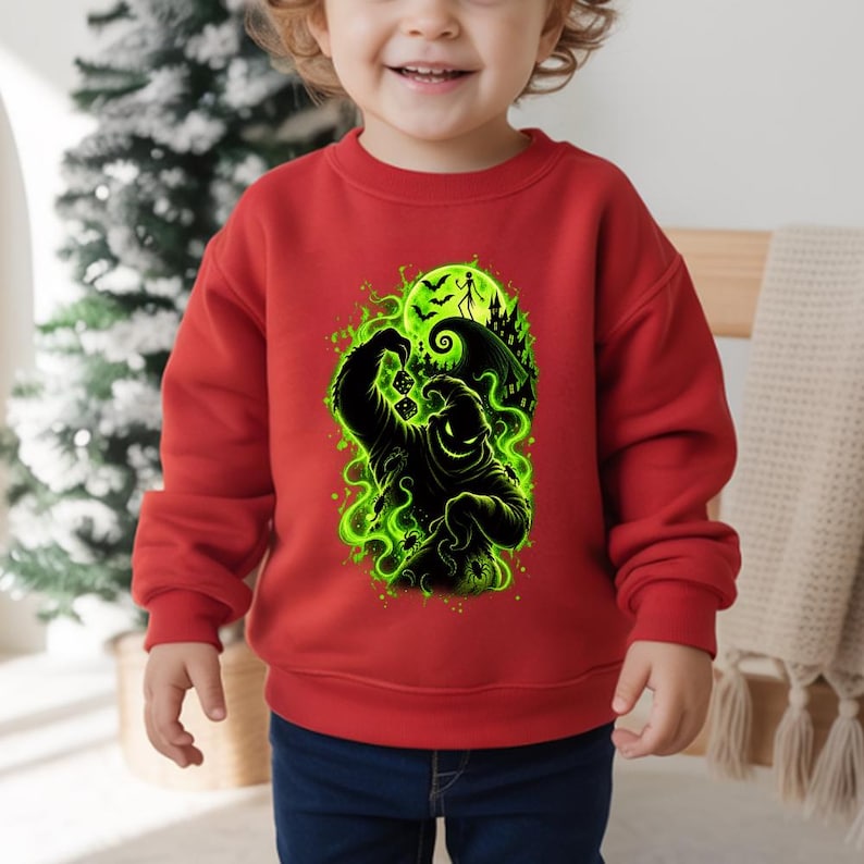May include: A bright red long-sleeve sweatshirt featuring a graphic print of a black Oogie Boogie character holding dice, surrounded by vibrant green swirling smoke, bats, a full moon, and a spooky house silhouette on the front center.