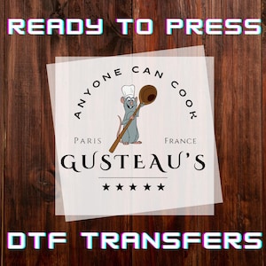 May include: DTF transfer featuring a cartoon rat chef holding a wooden spoon, with the text "Anyone Can Cook" and "GUSTEAU'S PARIS FRANCE". The words "READY TO PRESS" and "DTF TRANSFERS" are also displayed.