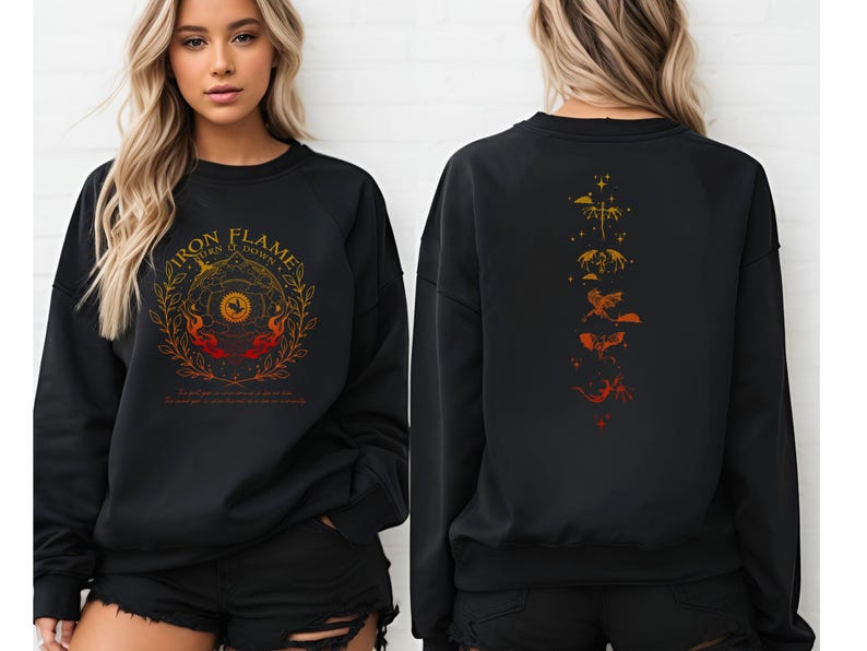 Op de afbeelding: Zwart sweatshirt met de tekst "IRON FLAMES TURN O DOWN" in goud en oranje. Het ontwerp aan de voorkant toont een cirkelvormig embleem met vlammen en een vogel. De achterkant heeft een verticaal ontwerp van gestileerde draken in tinten oranje en goud.