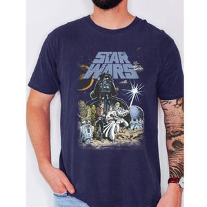 May include: Navy blue Star Wars graphic t-shirt featuring Darth Vader, the Star Wars logo, and other characters. The design is a vintage-style illustration with a space theme.