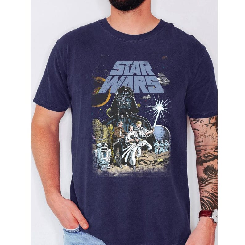 May include: Navy blue Star Wars graphic t-shirt featuring Darth Vader, the Star Wars logo, and other characters. The design is a vintage-style illustration with a space theme.