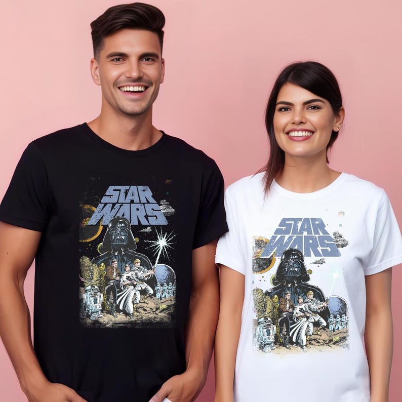 May include: Black and white Star Wars t-shirts. The black shirt features a graphic of Darth Vader and other characters. The white shirt has the same design. Both shirts have the Star Wars logo in blue and grey.