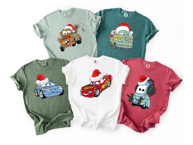 A collection of t-shirts featuring various cartoon car characters, including Cars, in festive holiday-themed designs.
