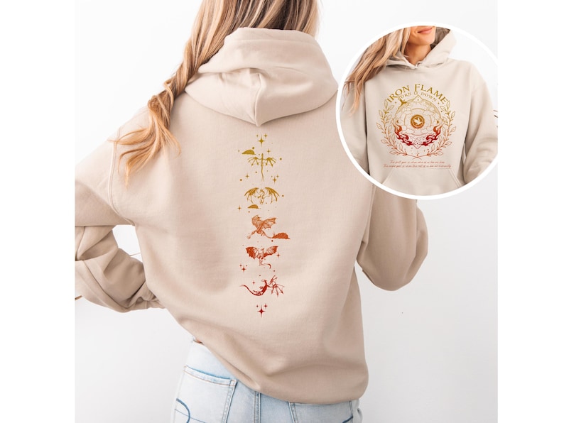Op de afbeelding: Beige hoodie met een drakenontwerp op de rug in tinten oranje en rood. Het ontwerp toont een reeks gestileerde draken. Een kleinere afbeelding op de voorkant toont een cirkelvormig ontwerp met de woorden "Iron Flame" en een decoratieve rand.