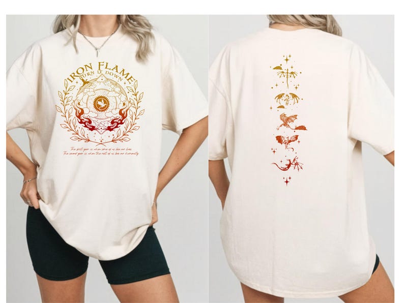 Op de afbeelding: Cr&egrave;mekleurig T-shirt met een grafische print op de voorkant met de tekst "IRON FLAME" en een cirkelvormig ontwerp met vlammen en botanische elementen. De achterkant van het shirt toont een verticale opstelling van gestileerde draken en sterren in oranje en goud.