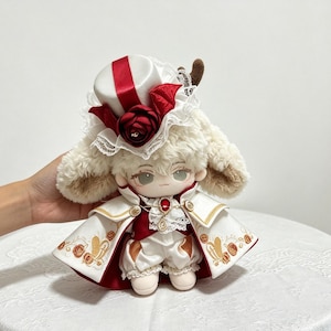 May include: A plush doll with cream-colored fur, wearing a white and red cape with gold embroidery, a white top hat adorned with a red rose and lace, and a red vest with a central red gemstone pendant. The doll features large ears and white pants.