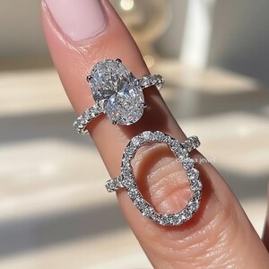 Peut inclure: Deux bagues en diamant. La bague supérieure présente un diamant de taille ovale avec un halo et un pavage de diamants. La deuxième bague a une forme ovale incrustée de diamants. Les deux bagues sont serties dans un métal argenté.