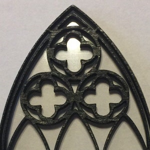 May include: Black wooden frame with a three-part arched window design. The frame has a decorative, intricate pattern of overlapping quatrefoils.