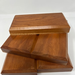 May include: Four wooden display risers stacked on top of each other. The risers are made of a light brown wood with a smooth finish.