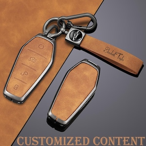 May include: Tan leather key fob covers and a key chain with a metal clasp. The key fob covers have a silver metal frame and embossed symbols. The key chain strap is engraved with the name "Elizabeth Taylor". The words "CUSTOMIZED CONTENT" are at the bottom.