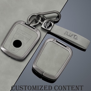 May include: A gray key fob cover set with a matching strap. The key fob cover has a car outline and a black circle. The strap is engraved with "Elizabeth Taylor". The set is connected with a silver carabiner. The words "CUSTOMIZED CONTENT" are at the bottom.