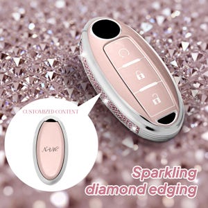 Peut inclure: Un étui de clé de voiture rose doré avec une bordure argentée et des bordures en diamant étincelantes. Le couvercle comporte trois boutons et un petit insert avec le texte "CUSTOMIZED CONTENT". L'étui de clé est présenté sur un fond rose étincelant.