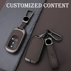 May include: Two brown and silver car key fobs with keychains. One fob has buttons and a red display. The other fob has a leather strap with the initials "MF" on it. The text "CUSTOMIZED CONTENT" is at the top.