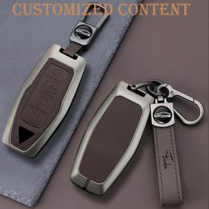 May include: Two car key fobs with a silver-tone metal frame and brown leather inserts. One fob has buttons, the other has a leather strap with the word "Freedom". The text "CUSTOMIZED CONTENT" is at the top.