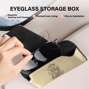 May include: A gold-coloured eyeglass storage box with a black interior and a magnetic closure. The exterior features a line drawing of a dog riding a motorcycle. Text includes EYEGLASS STORAGE BOX, Magnetic Opening And Closing, Flocked Inner Lining, and Clip-on Installation.