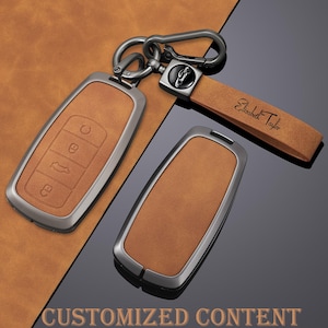 May include: Tan leather car key fob covers with a silver metal frame. One fob has embossed buttons, and another has a matching leather strap with the name "Elizabeth Taylor". The image also includes the text "CUSTOMIZED CONTENT".
